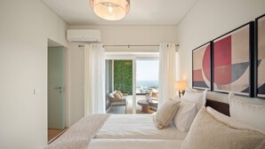 A hotel room with a bed, a balcony with a view, and a painting on the wall. - An amazing apartment with Ocean and Estoril view (Cascais)