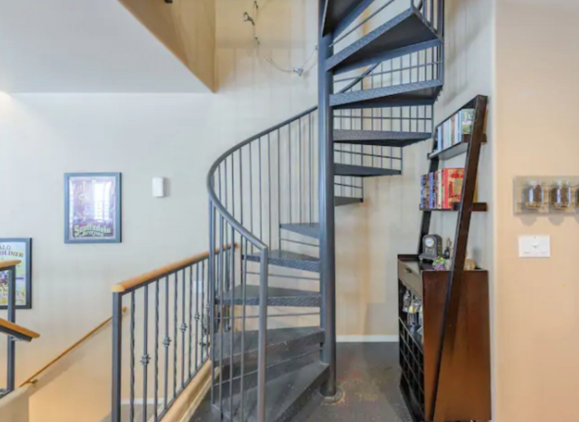 A spiral staircase with metal railings and wooden handrails, leading to an upper floor.