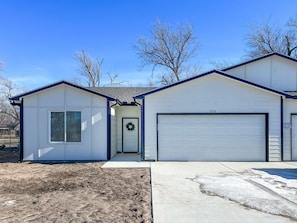 A single-story building with a garage, a front door with a wreath, and a number '212' on the garage door.