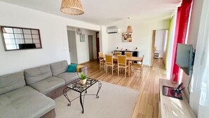 A living room with a sofa, coffee table, and dining area with chairs. - 3bedroom apartment, private garden, free parking, EV charger, AC, wifi, quiet. (Toulon)