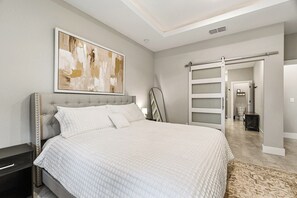 A bedroom with a large bed, a sliding closet door, and a modern abstract painting on the wall. - Luxury Healing Retreat North Port (North Port)