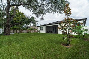 A modern house with a covered patio, a fenced yard, and a tree. - Luxury Healing Retreat North Port (North Port)
