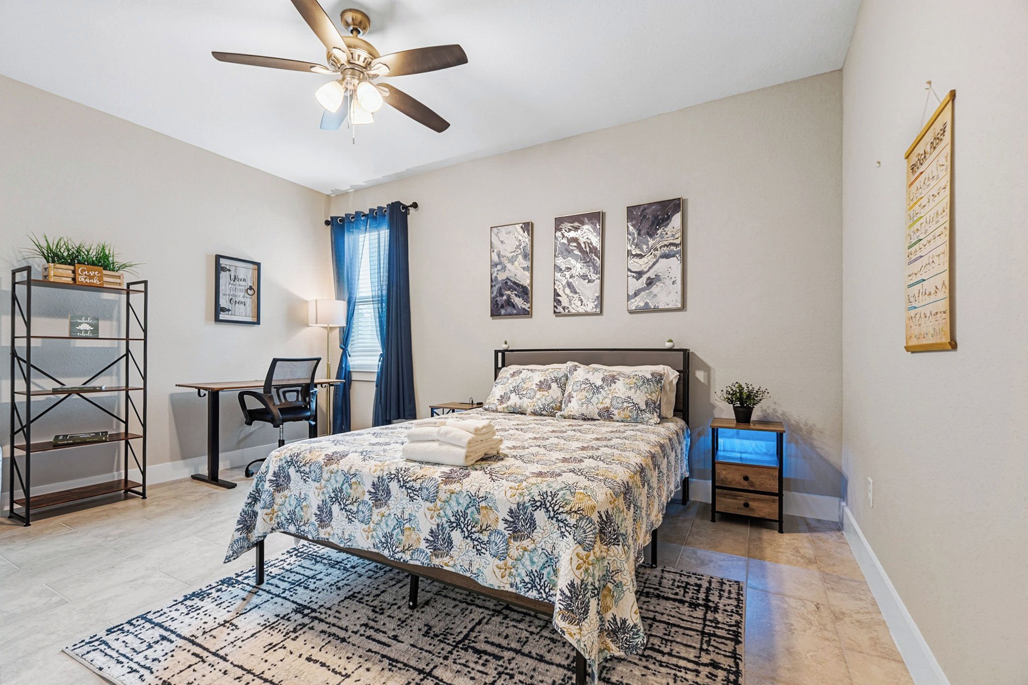 A bedroom with a bed, a desk, a chair, a shelf, and a ceiling fan.