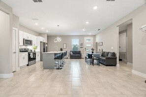 A spacious kitchen with modern appliances, a central island, and a dining area with a sofa and chairs.
