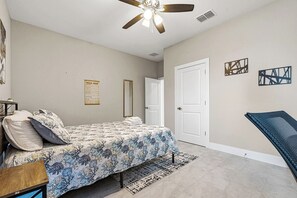 A bedroom with a bed, a ceiling fan, a door, and a wall-mounted mirror. - Luxury Healing Retreat North Port (North Port)