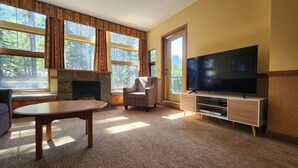 A living room with a fireplace, a television, a sofa, and a dining table.