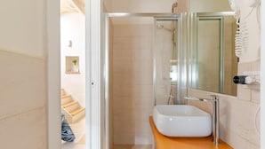 A modern bathroom with a glass shower enclosure, a white sink, and a wooden vanity. - Residenza Già Antico Forno (Matera)