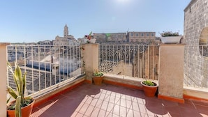 A rooftop terrace with a clear view of the cityscape, featuring a church and residential buildings. - Residenza Già Antico Forno (Matera)