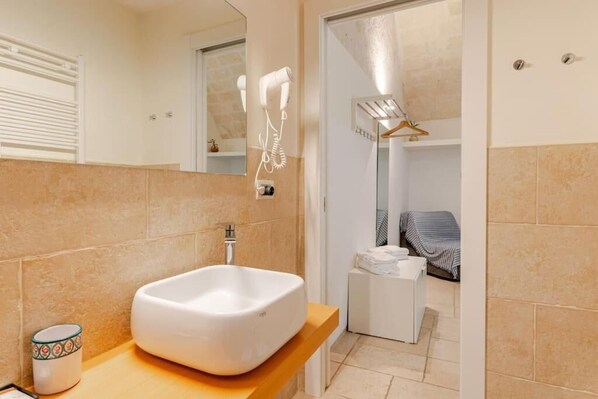 A modern bathroom with a large white sink, a towel rack, and a mirror. - Residenza Già Antico Forno (Matera)