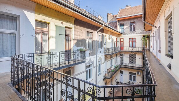 Un immeuble à plusieurs étages, doté de balcons, d’un escalier et d’une ruelle étroite.