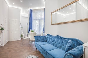 Una sala de estar moderna con un sofá azul, paredes blancas y un espejo grande.