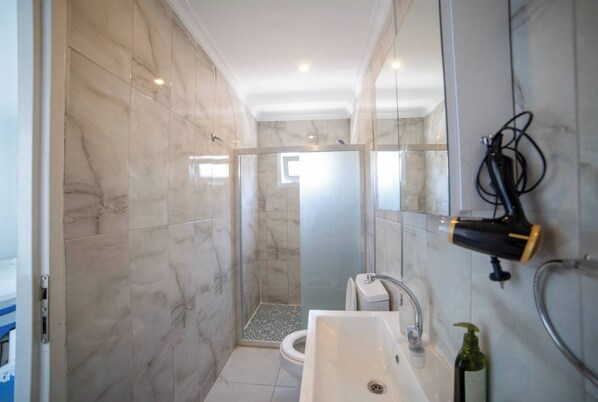 A modern bathroom with a shower, toilet, and sink. - Assostik Otel (Ayvacık)