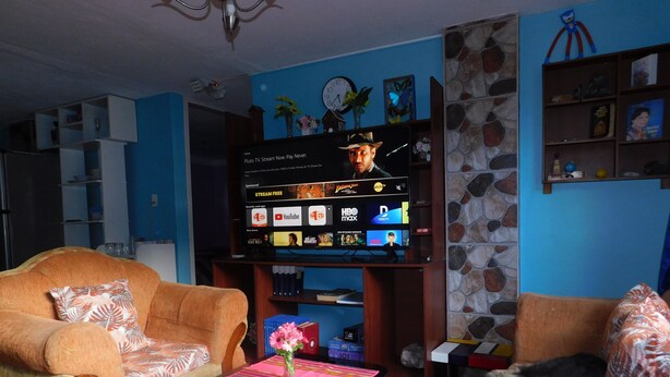A living room with a TV displaying a streaming service interface, a sofa, a coffee table with a vase, and a bookshelf. - Central Department in Baños (Baños de Agua Santa)