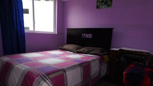 A bedroom with a bed, a dresser, and a window. - Central Department in Baños (Baños de Agua Santa)