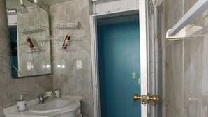 A bathroom with a sink, mirror, and storage shelves. - Central Department in Baños (Baños de Agua Santa)