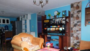 A living room with a sofa, a coffee table, a TV, and a dog. - Central Department in Baños (Baños de Agua Santa)
