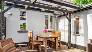An outdoor patio with a wooden table and chairs, a flower vase, and a pergola structure. - 3 bedroom lovely home in Ulfborg (Ulfborg)