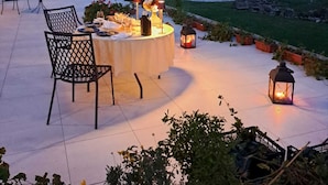An outdoor dining area with a round table set for two, surrounded by chairs, and illuminated by candles and lanterns. - Le Case Residenza di Campagna (Assisi)