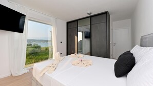 A bedroom with a large bed, a TV, and a view of the sea. - Amazing home in Ljubac (Ljubac)