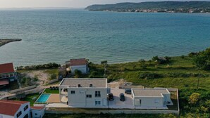 A coastal property with a swimming pool, a small garden, and a view of the sea and distant hills. - Amazing home in Ljubac (Ljubac)