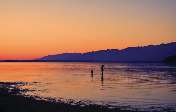 A sunset over a calm body of water with mountains in the background.