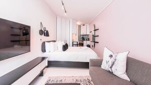 A modern bedroom with a bed, bedside tables, a sofa, and a large mirror. - Flamingo - Sea Point Lions View (Cape Town)