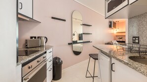 A modern kitchen with stainless steel appliances, a granite countertop, and a large mirror. - Flamingo - Sea Point Lions View (Cape Town)