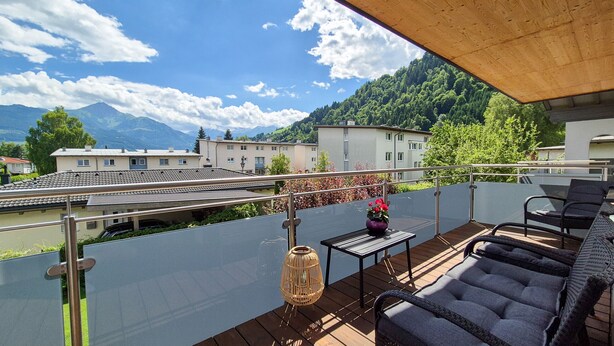 Un balcon avec vue sur une rivière, des bâtiments et des montagnes.