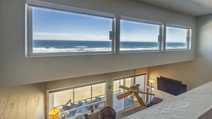 Una habitación con vistas al océano a través de tres amplios ventanales.