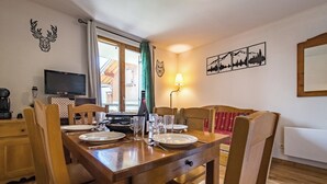 A dining area with a wooden table set for four, a television, and a lamp. - Apartment for 4 to 6 people in Albiez (Albiez-Montrond)