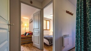 A hallway leading to a bedroom with a wooden floor, a bed, a nightstand, a lamp, and a window. - Apartment for 4 to 6 people in Albiez (Albiez-Montrond)