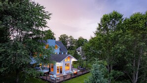 Een tweelaags huis met een terras, omringd door bomen.