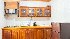 Eine Küche mit Holzausstattung, einem Gasherd, einer Mikrowelle und einem Kühlschrank.