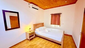 Ein Schlafzimmer mit einem hölzernen Bett, einem Nachttisch, einer Wand-Klimaanlage und einem fensterbelaubten Fenster.