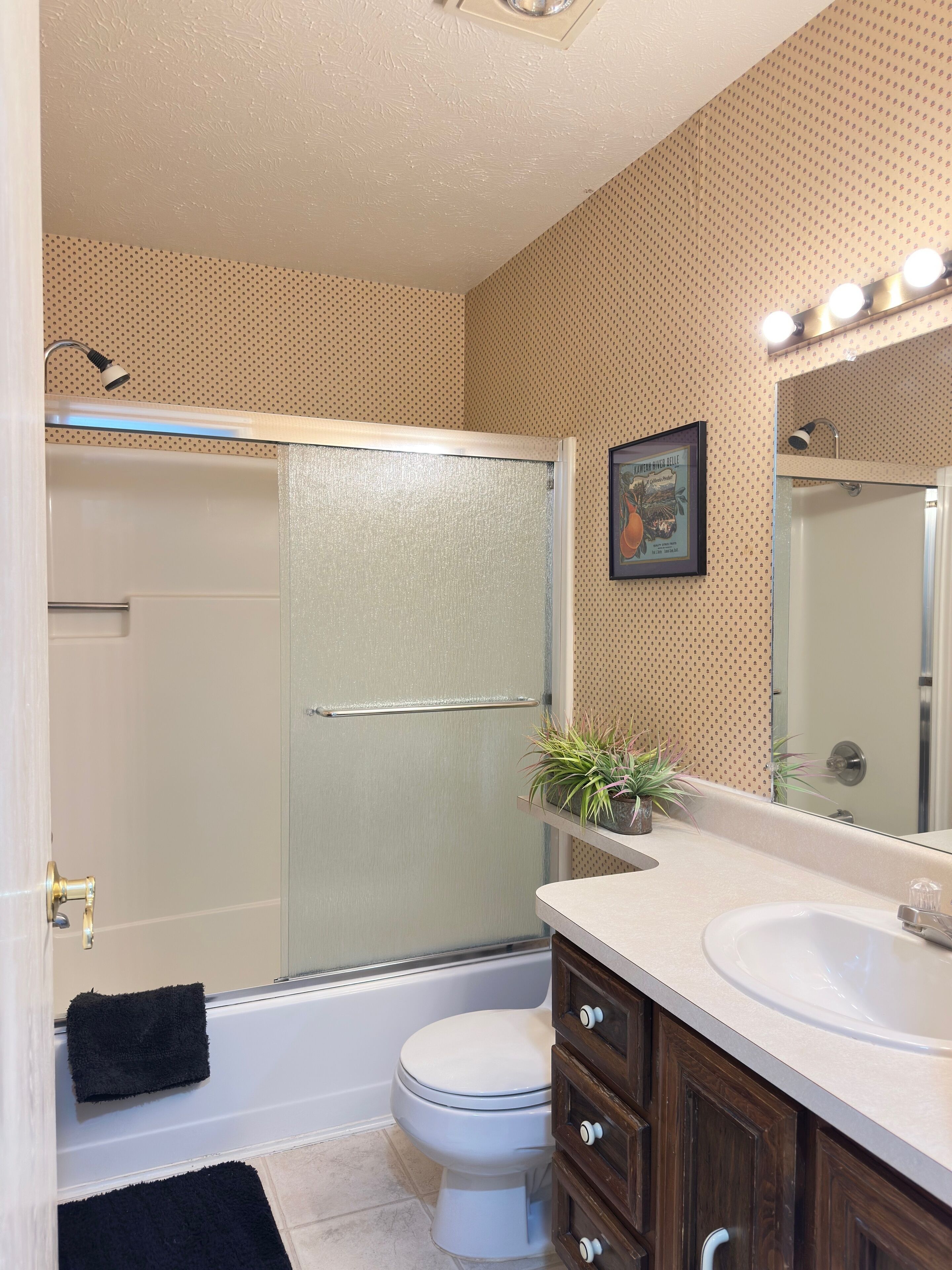 Une salle de bain équipée d’une douche, de toilettes, d’un lavabo et d’un miroir avec éclairage.