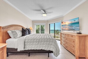 A bedroom with a bed, a ceiling fan, a TV, and a balcony with a view of the ocean. - Land's End 11-306 Beach Front - Premier (Treasure Island)