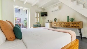 Un dormitorio con una cama grande, cabecera de madera, un escritorio con cajones, un televisor y una escalera.