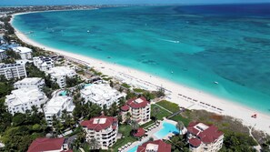 A resort with multiple buildings, a beach, and a clear blue sea.