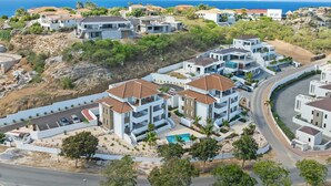 A coastal residential area with modern houses, a curved road, and a swimming pool. - Palm Paradise-Stylish Island Live-Blue Bay Curaçao (Willemstad)