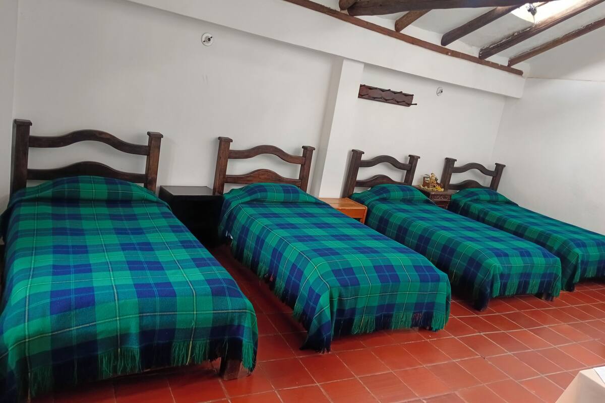 A room with four wooden beds, each with a green and blue checkered bedspread.