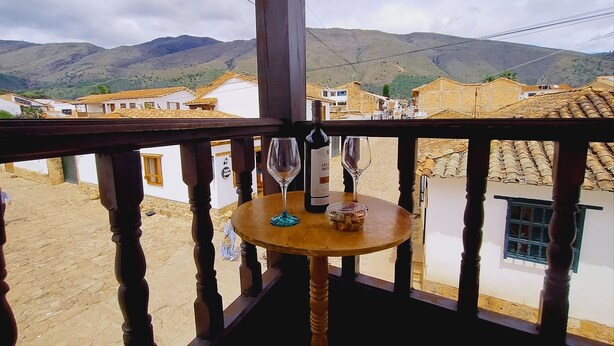 A balcony with a table, two wine glasses, and a bottle of wine.