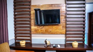 A wooden TV stand with a flat-screen TV mounted on a brick wall.