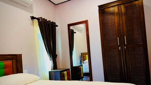 A bedroom with a bed, a wardrobe, a mirror, and a curtain.