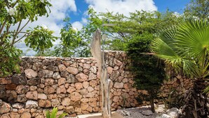 Un mur de pierre, une structure en bois et un palmier, le tout dans un cadre de jardin.