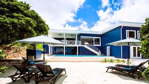 Un bâtiment à deux étages doté d’une piscine, d’un espace extérieur aménagé et d’un escalier menant à l’étage supérieur.