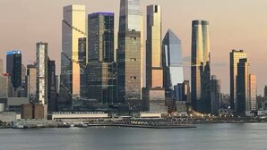 A city skyline with modern skyscrapers, a waterfront, and a clear sky.