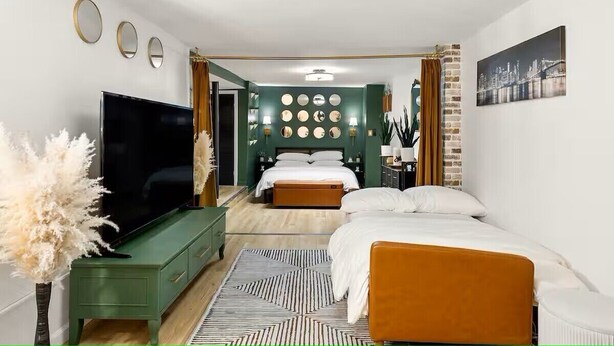 A modern bedroom with a bed, a TV, and a green dresser.