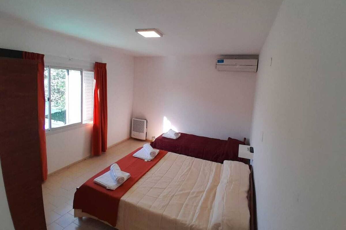 Een kamer met twee bedden, een raam met gordijnen, een plafondlamp en een airconditioning.