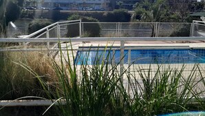 A swimming pool with a view of surrounding buildings and a distant tower. - HOTEL CRISTAL (Villa Carlos Paz)