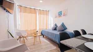 Une chambre moderne équipée d’un lit, d’une table à manger et d’un petit coin salon.